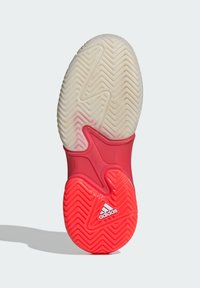 Suela de zapatilla de goma con una entresuela blanca, acentos rojos, patrón de agarre texturizado y un logo de adidas en relieve cerca del talón.