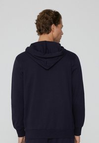 Námořnická modrá mikina s kapucí a uvolněným střihem, s dvojitě vrstvenou, nastavitelnou kapucí a žebrovanými manžetami a lemem. Hladká textura.