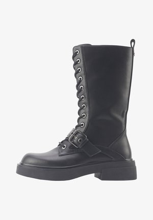 Cizme de luptă negre, până la genunchi, cu șireturi, fabricate din piele sintetică texturată, având o talpă groasă și o curea ajustabilă cu detaliu de cataramă.