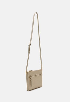 Beige lille crossbody taske med lang justerbar rem og forreste lynlåslomme, vist mod en ensfarvet lys baggrund.