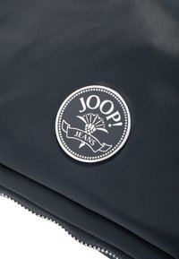 Tessuto nero testurizzato con un logo circolare JOOP! Jeans e un bordo decorativo e dettagli accentuati. Dettaglio con zip sul bordo.