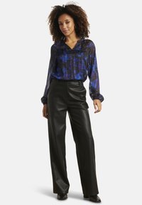 Black faux leather wide-leg pants paired with a blue and black patterned long-sleeve blouse featuring a V-neck and cuffed sleeves.