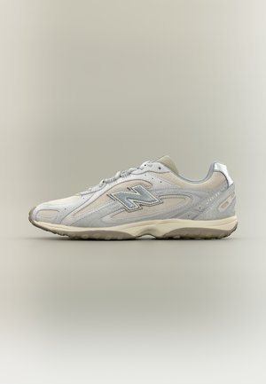 Ανοιχτό γκρι και μπεζ αθλητικό παπούτσι New Balance 2041 με ανακλαστικό λογότυπο "N" και υφιστάμενη σόλα, εμφανίζεται σε πλάγια όψη σε απλό φόντο.