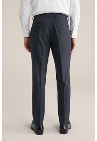 Tummansiniset räätälöidyt housut, joissa on tekstuuri, kaksi takataskua ja suora leikkaus, yhdistetty mustiin juhlakenkiin.