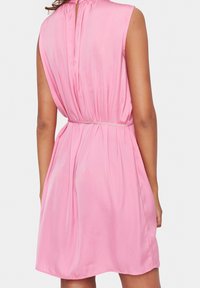 Vestido rosa con mangas cortas, espalda fruncida, textura suave y un cinturón en la cintura sutil. Presenta una pequeña apertura en forma de llave en la parte posterior.