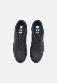 Baskets en cuir bleu marine avec des détails perforés et des lacets ton sur ton. Elles disposent d'une semelle blanche contrastante et d'un logo bien visible sur la semelle intérieure.