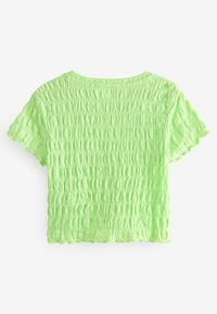 Top corto de manga corta en tejido texturizado de color verde claro con apariencia arrugada y bordes en forma de scallop, que presenta un escote redondo.