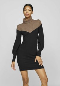 Abito in maglia con alto collo a imbuto marrone e corpo nero, caratterizzato da maniche a palloncino e un design a blocchi di colore a forma di V. Texture liscia.