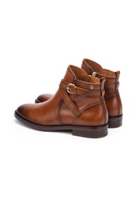 Brown leather ankle boots with a rounded toe, side zipper, and buckle detail. Stitched accents and a low stacked heel.