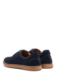 Zapatos de ante azul marino con un diseño texturizado, puntera redonda, suela de goma marrón y sutiles acentos de costura. Cierre con cordones en la parte frontal.