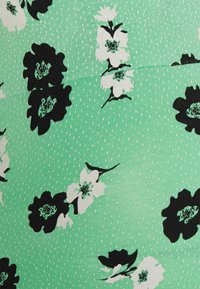 Tecido de vestido floral com fundo verde menta, flores pretas e brancas, textura pontilhada e realces em rosa claro.