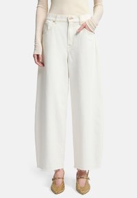 Pantaloni larghi in denim bianco con vita alta, tasche frontali e orlo sfilacciato. Il tessuto ha una texture liscia e chiusura con bottone classico.