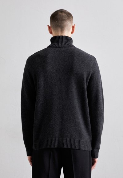Tamsiai pilkas megztas turtleneck kelnaitė su grublėta apykakle ir apatine dalimi. Yra laisvas jautis ir sklandus paviršius, matomas iš galinio vaizdo.