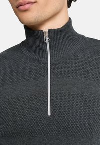 Harmaa vetoketjullinen puuvillapaita, jossa on ribbikuvioitu kaulus, tekstuurillinen pinta ja hopeinen vetoketjkoristelu edessä.