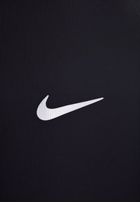 Tela negra de Nike con una superficie texturizada, que presenta un destacado logo plateado de Swoosh en el lado derecho.