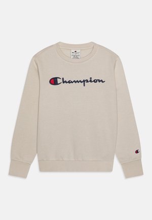 Beżowa bluza z długim rękawem z logo Champion w kolorze granatowym i czerwonym umieszczonym na środku klatki piersiowej oraz mniejszym logo na mankiecie lewego rękawa.