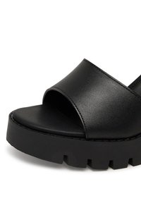 Sandalie negre cu vârf deschis, fabricate dintr-un material sintetic neted, având o curea lată și o talpă texturată groasă.