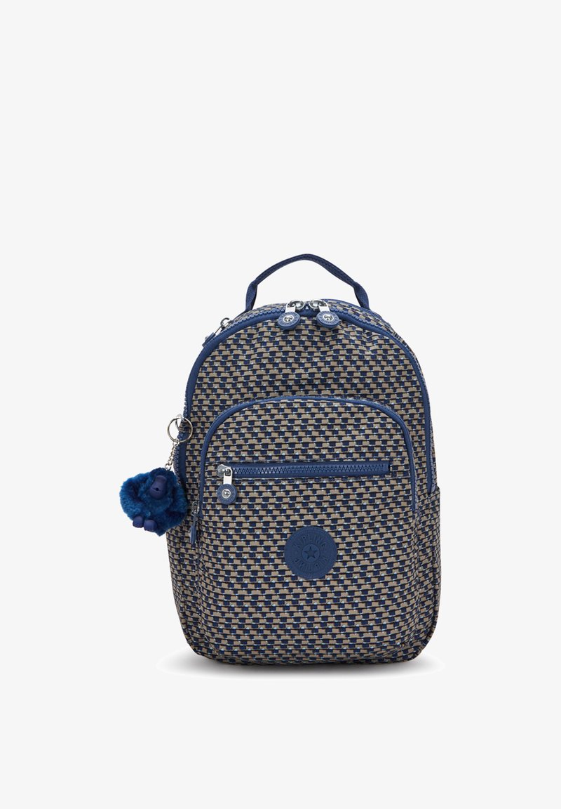 Mochila tejida en azul marino y beige con forma redondeada, asa superior, dos compartimentos con cremallera y un llavero con pompón azul adjunto.