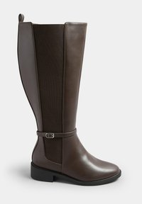 Wysoki, ciemnobrązowy skórzany but z elastycznym bocznym panelem, niskim obcasem, okrągłym czubkiem oraz dekoracyjnym paskiem ze srebrną klamrą wokół kostki.