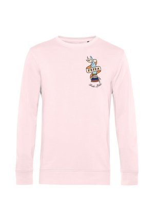 Jasnoróżowa koszula z długim rękawem z wzorem dłoni w stylu tatuażu trzymającej baner z napisem "FRIDA" oraz napisem "Frida Kahlo" poniżej.