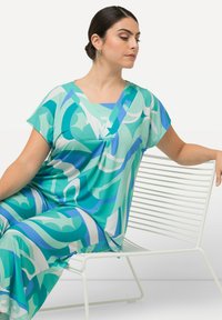 Conjunto holgado de manga corta en azul verdoso y azul claro con patrones abstractos en espiral. La tela liviana cae elegantemente, con un escote en V.