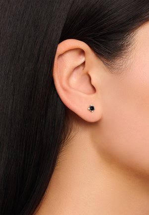 Schwarze Steinstifte mit einer floral gestalteten silberfarbenen Fassung. Die Ohrringe sind klein und verfügen über klare Akzente rund um den Mittelstein.