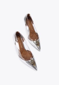 Pompes argentées métalliques à bout pointu avec panneaux latéraux transparents et semelle intérieure rembourrée marron. Comprend des embellissements en métal doré ressemblant à un hérisson.