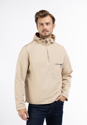 Beige lichtgewicht gewatteerde jas met een half-rits aan de voorkant, voorzien van een borstzak met rits en een gladde, glanzende textuur.