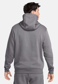 Felpa grigia con un grande cappuccio strutturato e polsini a costine. Realizzata in tessuto morbido, presenta un design minimal e una vestibilità comoda.