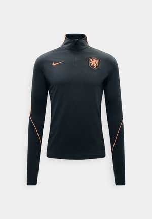 Haut de sport noir à manches longues avec le logo Nike orange et le blason du lion des Pays-Bas, doté d'un col à zip quart et d'un liseré orange sur les manches.