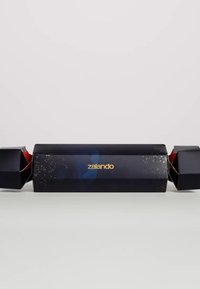 Coriandolo di festa nero con accenti dorati e un design blu, con estremità rosse. Il nome del marchio "zalando" è visualizzato in modo prominente in oro.
