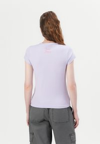 Alyvinė prigludusi marškinėliai su trumpomis rankovėmis, apvaliu kaklu, ant nugaros išsiuvinėta "Love Juicy" rožinės spalvos. Lygi tekstūra, minimalus dizainas.