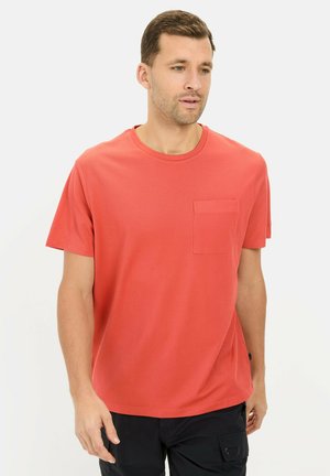 Rode katoenen T-shirt met korte mouwen, ronde hals en een borstzak. Het heeft een gladde textuur en een relaxte pasvorm, gedragen met zwarte cargobroeken.