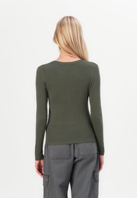 Langarmige, olijfgroene shirt met een ronde hals en een getailleerd ontwerp. De stof ziet er soepel en lichtgewicht uit. Geen zichtbare patronen of hardware.