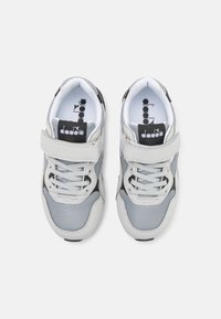 Sneakers grigi con una combinazione di materiali in rete e sintetici. Presentano lacci e un cinturino in velcro. Logo nero e bianco sulla linguetta.