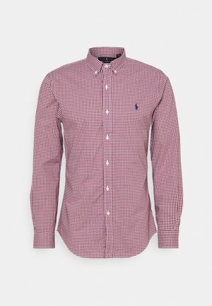 Chemise à manches longues à boutons avec motif à carreaux rouges et blancs et petit logo brodé sur la poitrine gauche.