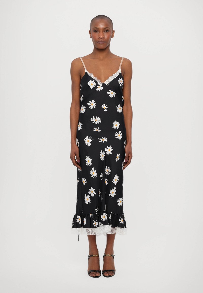 Robe noire avec imprimé marguerites blanches, accents en dentelle, bretelles spaghetti ajustables et ourlet volanté. Le tissu semble lisse et léger.
