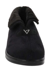Zwarte slipper met een zachte, gestructureerde bovenkant, ronde vorm en nep bontvoering. Beschikt over een kleine versiering in de vorm van een driehoek.