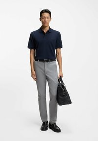 Granatowa koszulka polo z krótkim rękawem, szare dopasowane spodnie, czarny pasek, czarna skórzana torba i czarne buty. Gładka tkanina o klasycznym kroju.