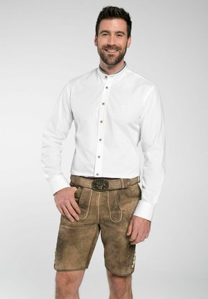 Weißes Langarmhemd mit Kragen und braunen Knöpfen, kombiniert mit braunen Leder-Shorts mit dekorativen Nähten und einem Gürtel mit metallichem Schnallenverschluss.