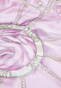 Bufanda de seda de color rosa claro con un patrón de cadenas y detalles en dorado, y un logotipo central en un diseño circular. Textura suave y apariencia fluida.