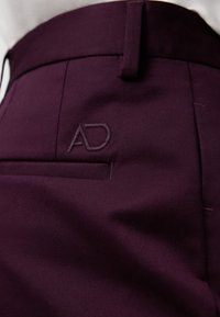Pantaloni bordeaux con una vestibilità su misura, dotati di un sottile logo AD ricamato sulla tasca posteriore e di un tessuto liscio e strutturato.