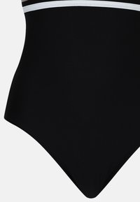 Sort badedragt i ét stykke med glat tekstur, der har hvide vandrette striber over øverste område og klassisk højt skåret ben.