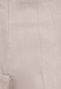 Tissu beige avec des lignes de couture verticales et une texture subtile, montrant un gros plan détaillé du matériau et du design des coutures.