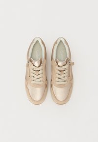 Béžové tenisky s metalickým leskem a texturovanou tkaninou, které mají šněrovací design a boční zip pro snadné obouvání. Měkká vnitřní podšívka.