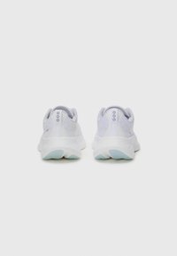 Zapatillas deportivas blancas con un empeine de tela suave, forma redondeada y talón texturizado. Suelas suaves con acentos azules, con una marca mínima.