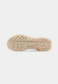 Beige sneaker sole with textured tread, orange logos, and grid pattern on a plain light gray background.
