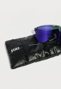 Gafas de sol deportivas con tintes morados reposando sobre un estuche suave acolchado negro con el texto "bliz Performance Eyewear".