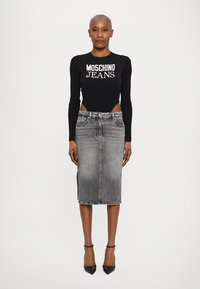 Top de manga longa preto com textura canelada e logótipo "MOSCHINO JEANS", combinado com uma saia midi de ganga cinza. A saia apresenta uma fenda lateral e um cós padrão.