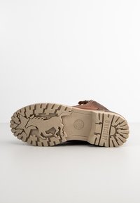 Brown leather shoe with a textured rubber sole featuring a horse graphic and star pattern, highlighting durability and grip.